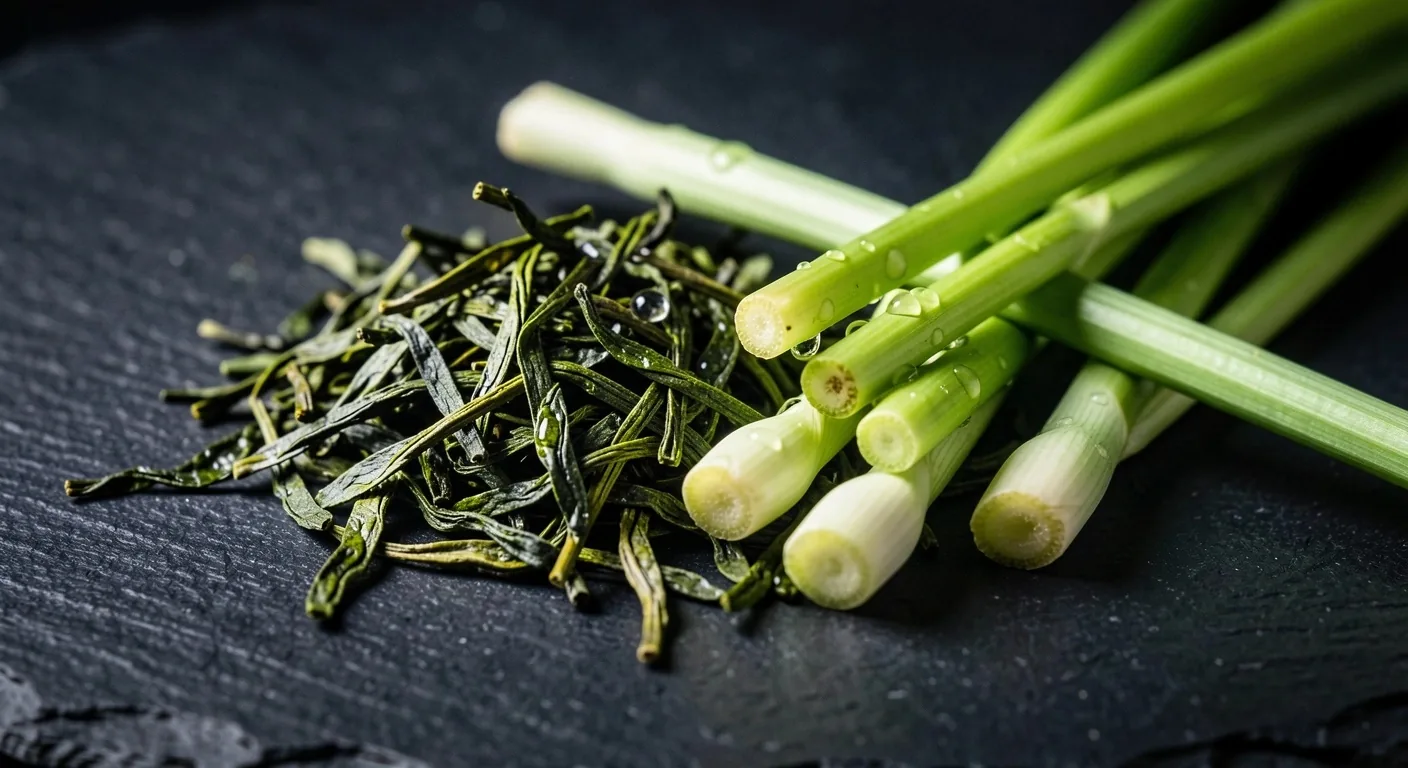 Loose green tea leaves and lemongrass on dark surface
